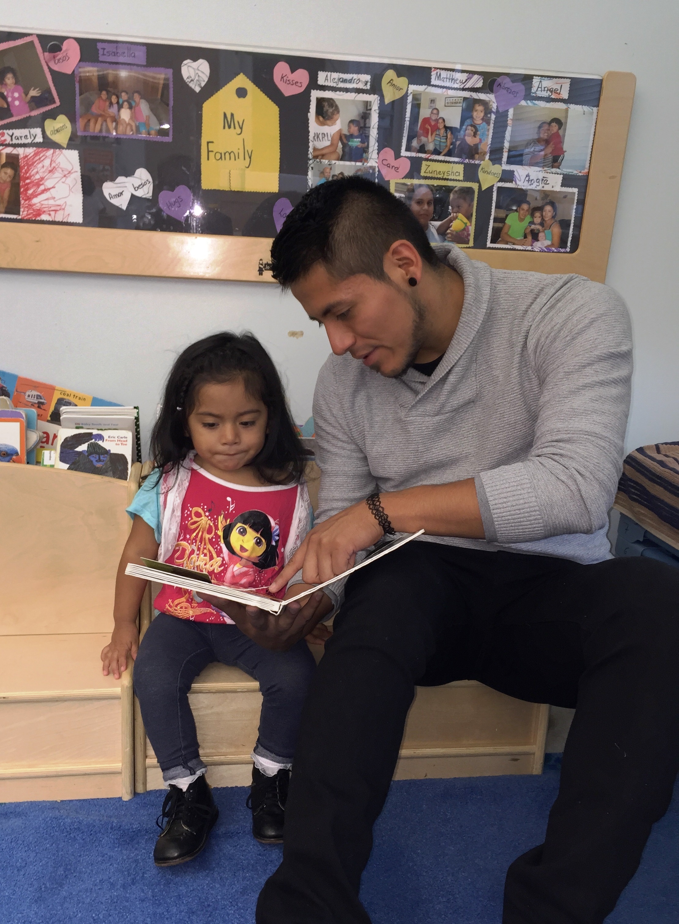 Man reads to child who is wearing a dora the explorer shirt